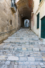 Fototapeta na wymiar Small street with cobblestone stairs in Unesco town Matera, Italy