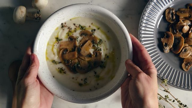 Healthy eating, serving mushroom soup in a bowl. Put on the table a bowl of creamy and rustic white soup with mushroom. Eating healthy vegetarian dinner. Cozy and warm food. Autumn warm puree.