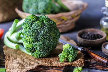 Photo of fresh broccoli around vegetables on cutting board. Raw Picture. Gray background. Image.