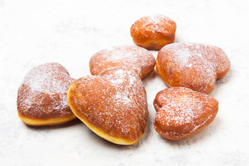 Homemade heart sheped donuts with powdered sugar on white background. Tasty doughnuts, copy space