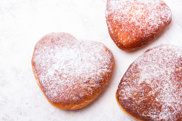 Homemade heart sheped donuts with powdered sugar on white background. Tasty doughnuts, copy space