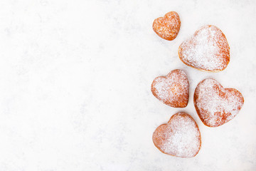 Homemade heart sheped donuts with powdered sugar on white background. Tasty doughnuts, copy space