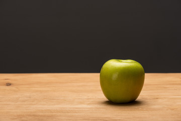 Green apple on wooden surface isolated on black