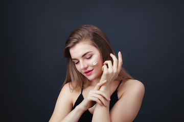 Lovely woman with smooth healthy skin applying cream on her face