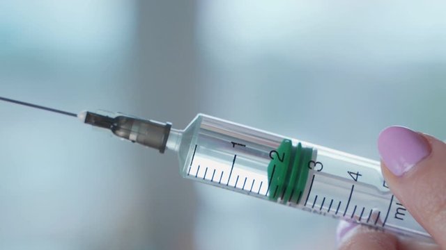 Close-up shot of syringe during injection, drug addiction problem, aids epidemic, vaccination. Medicine liquid delivering to patient body