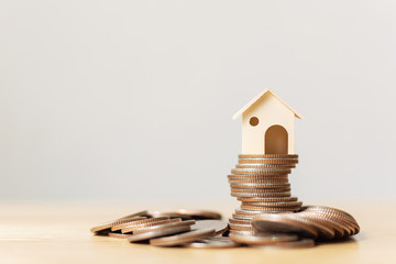 Property investment and home mortgage financial concept. Money coin stack with wooden house