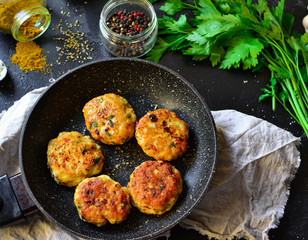 Meatballs in a pan. Chicken cutlets in a pan on a dark concrete table background. Top view. Ingredients and cooked meatballs. Spices, parsley, meat dish.