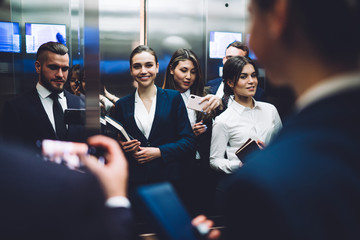 Happy coworkers taking selfie while standing in elevator together © BullRun