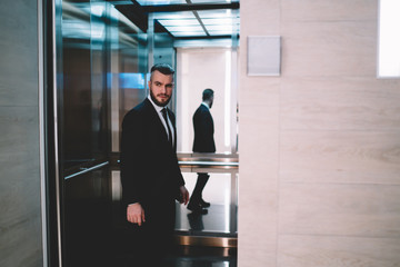 Businessman standing in opened elevator and looking away