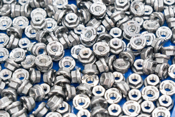 The pile of customize hexagon nut for special purpose in construction industry in the light blue scene.The industrial anti loose nut and bolt manufacturing concept.