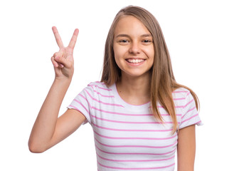Portrait of successful teen girl winner making Victory Gesture, isolated on white background. Beautiful caucasian young teenager. Happy cute child showing success sign and looking at camera.