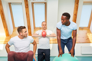 Gruppe junger Männer trainiert mit Gymnastikball