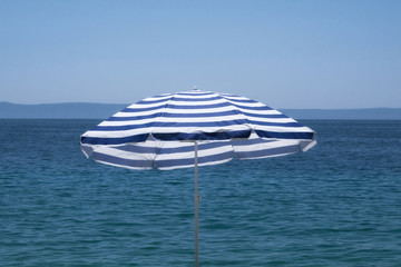 Blue umbrella on summer beach. Sea beach with sun umbrella waiting for tourists. Happy summer...
