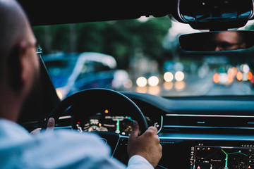Selective focus on automotive cockpit with dashboard during wheeling on highway road, cropped image of man driver getting to destination in expensive contemporary car, concept of executive transport