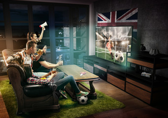 Fototapeta na wymiar Group of friends watching TV, match, championship, sport games. Emotional men and women cheering for favourite football team of Great Britain with flag. Concept of friendship, competition, emotions.