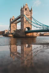 tower bridge in london reflected in the wet stone wall along the river thames