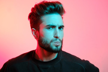 Beautiful caucasian young man portrait isolated on multicolored neon light backgroud. Young, smiling, surprised, screaming. Human emotions, facial expression concept. Trendy colors.Advertising concept