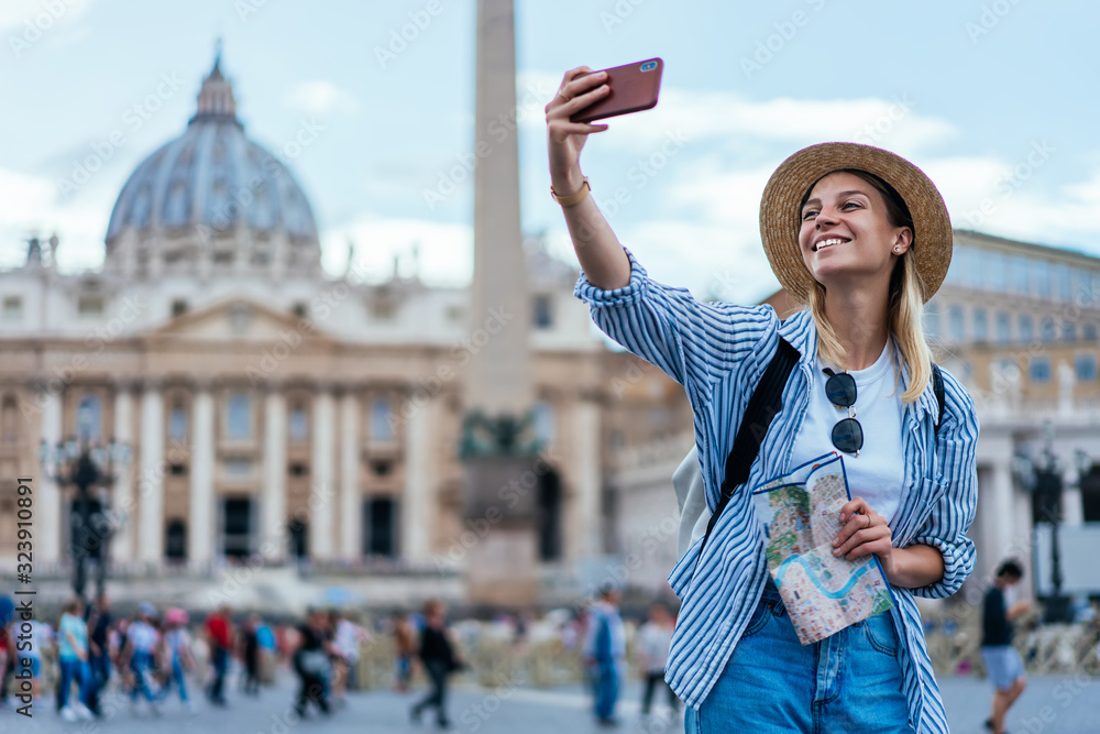 Poster cheerful woman in joyful mood holding navigation map and clicking cellphone images via medial applic