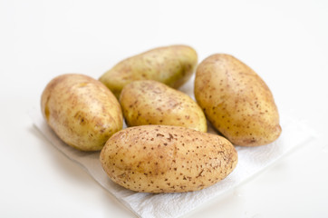 Fototapeta na wymiar Washed raw potatoes for cooking lie on a napkin on a white table