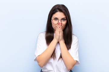 young pretty woman feeling worried, hopeful and religious, praying faithfully with palms pressed,...