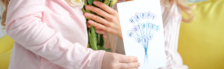Fototapeta premium panoramic shot of kid holding greeting card with happy mothers day lettering near mother