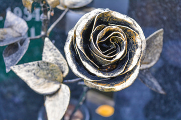 Old metallic rose flower on cemetery as sign of memory