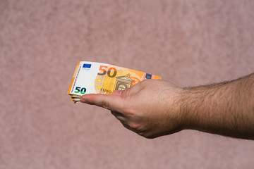 Hand holding showing euro money and giving or receiving money like tips, salary. 50 EURO banknotes...