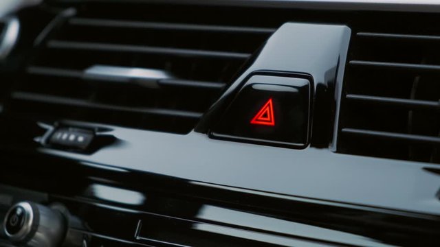 A man presses the emergency button in the car. Close up. Button blinks lights flash. Emergency incident.