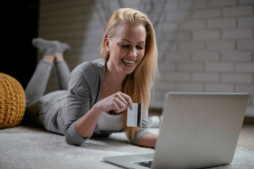 Girl is online shopping at home. Young woman holding credit card and using laptop computer. Online shopping concept	