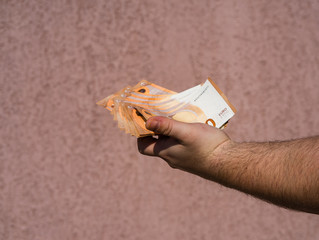 Hand holding showing euro money and giving or receiving money like tips, salary. 50 EURO banknotes...