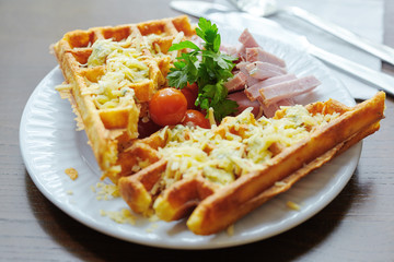 waffles covered with cheese with meat, parsley leaves on a plate