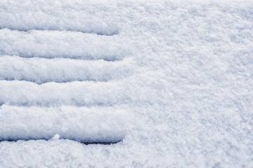 Fototapeta na wymiar Snow covered wooden bench in winter park on fluffy white snow background