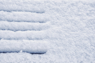 Snow covered wooden bench in winter park on fluffy white snow background