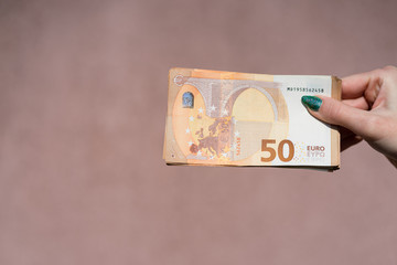 Hand holding showing euro money and giving or receiving money like tips, salary. 50 EURO banknotes...
