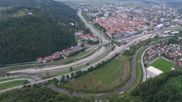 aerial drone shot above freeway and river running through countryside and town celje in slovenia