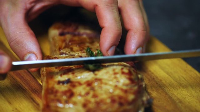 Close up shot hands slicing hot tasty steak cut with knife on a wooden board