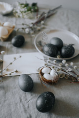 Easter table setting with gray textile napkin, quail and chicken eggs, blossom branch and mock up easter card. 