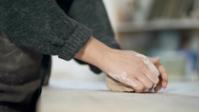 Close up footage of female hands mixinf clay on the work table. Slowmotion.