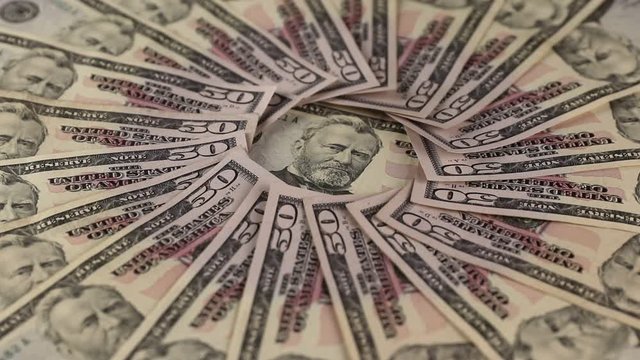 side view of background with cash fifty enty american dollars spinning,  in the center of flat lay composition is a portrait of president Ulysses Grant, concept of business and finance