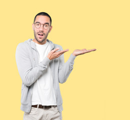 Surprised young man holding something with his hand