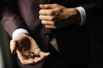 Close-up view of man's hands holding wedding rings.