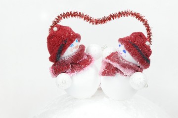  a pair of snowmen under the red outline of the heart