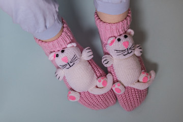 Legs of a girl in funny pink socks with cats in the blue background. Cozy slippers for the home.