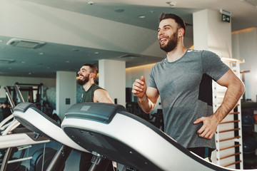 Two young man running on treadmill at gym