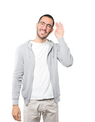 Happy young man smiling and making a gesture of trying to hear something