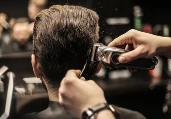 Fotobehang Kapsalon Men style. Close up photo of a barber’s hands working with electric shaver and comb to make a new hairstyle for a customer.  © My Ocean studio