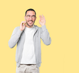 Fototapeta premium Happy young man smiling and making a gesture of trying to hear something