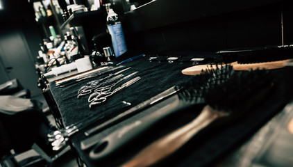 Fototapeta na wymiar Special tools. Side view of a barbershop hairstylist’s workplace with various professional tools, such as scissors and combs, on it.
