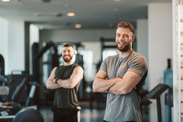 Two Handsome young man posing in a gym and looking at the camera with smile