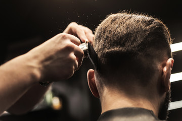 Cutting and combining. Close up photo of a man, who is having his hair trimmed on his nape with a comb and scissors.